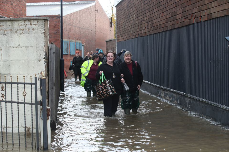  Workers walk through flood water as they in Doncaster