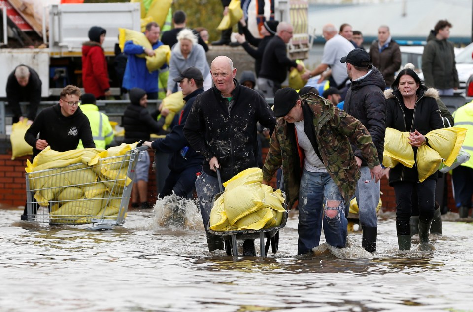  Residents carry sandbags in a flooded area of Bentley