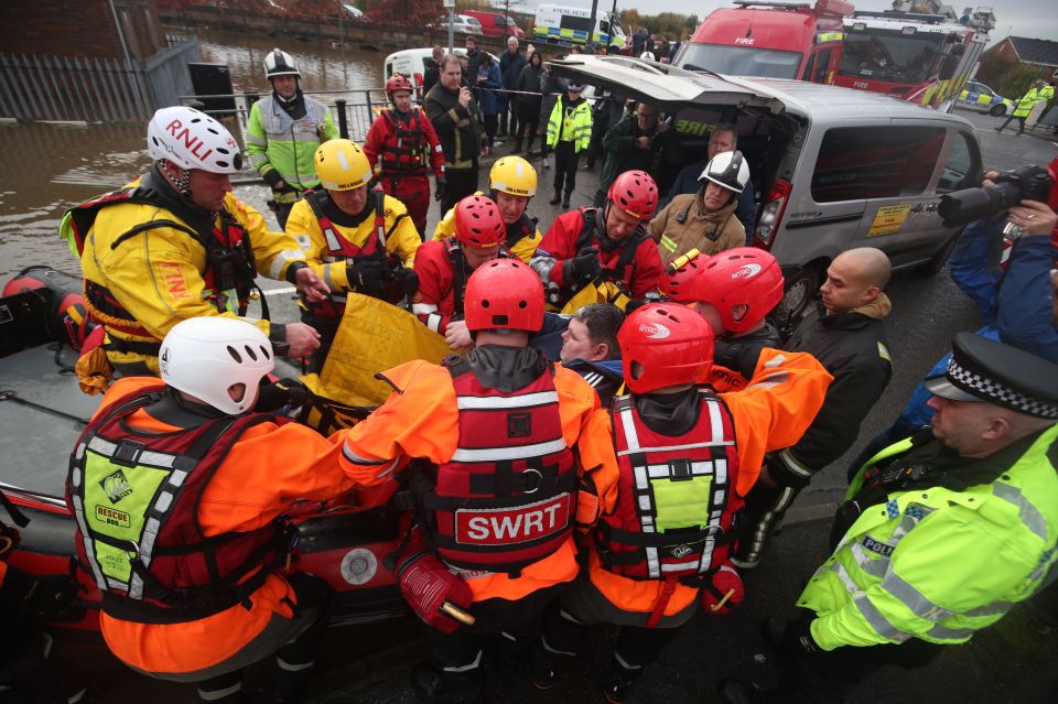  Rescue workers lift a man onto an inflatable boat as they battle to evacuate residents in Doncaster