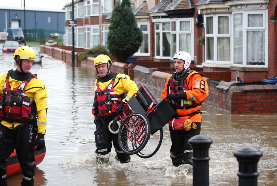  Firefighters carry a wheelchair to a disabled resident who was pulled to safety