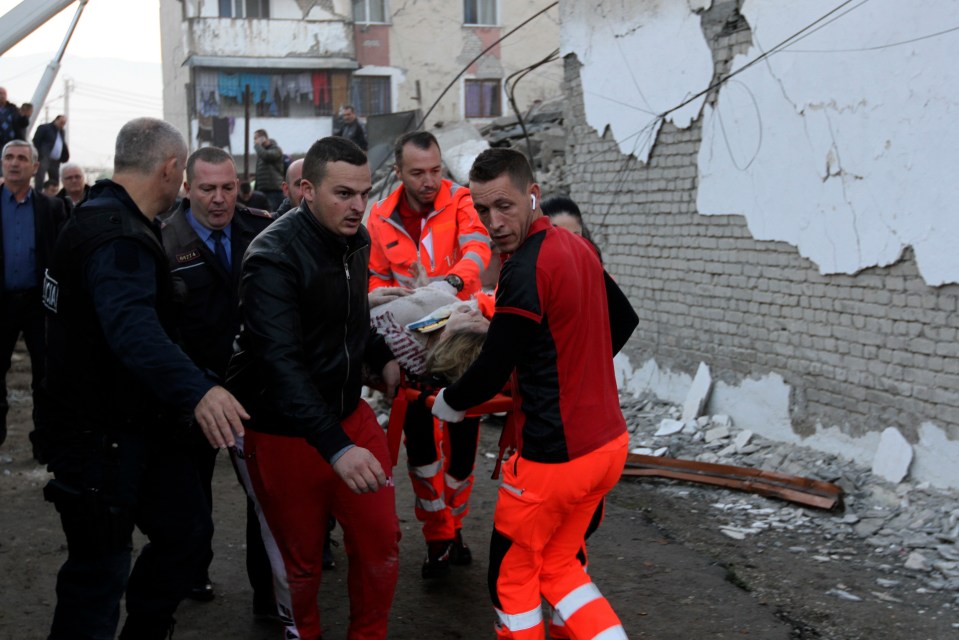  Rescuers carry an injured woman after a magnitude 6.4 earthquake in Thumane