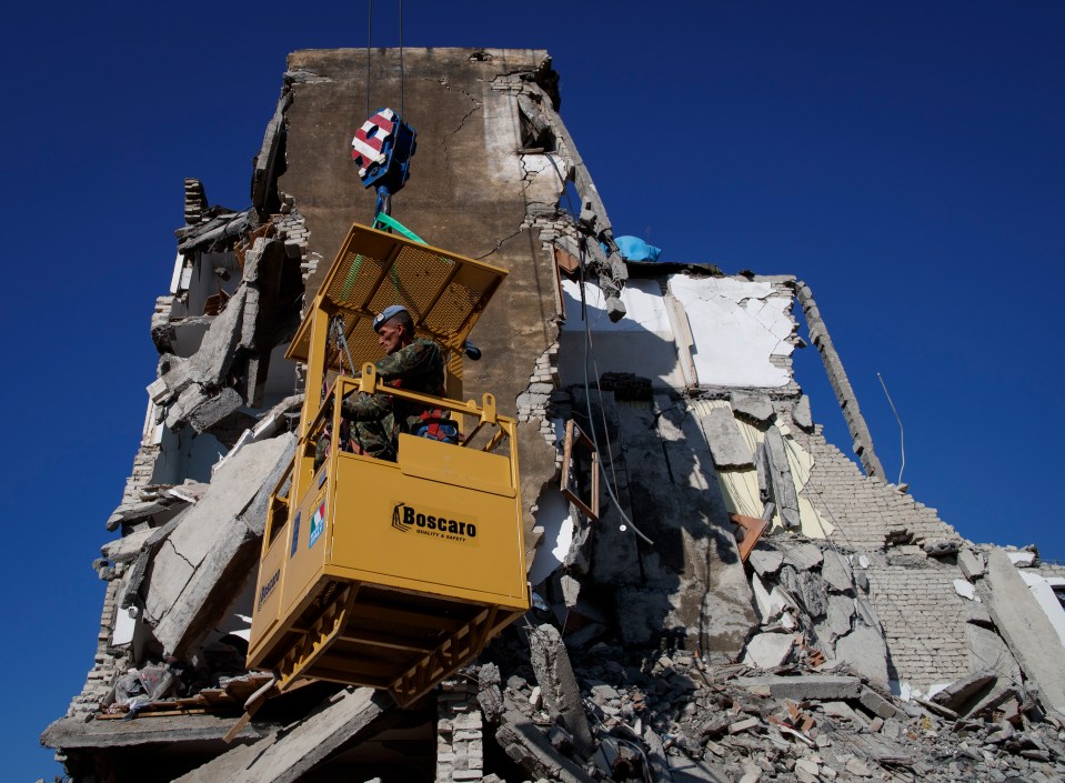  Albanian soldiers search for survivors in the rubble of a building