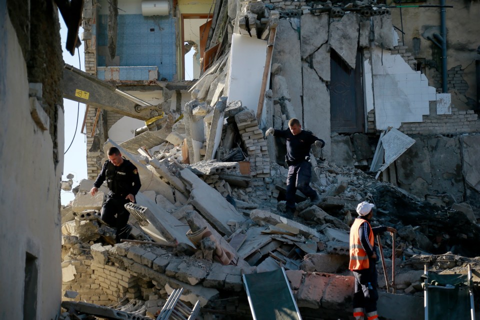  Emergency crews sift through the the rubble of a building in Thumane, Albania