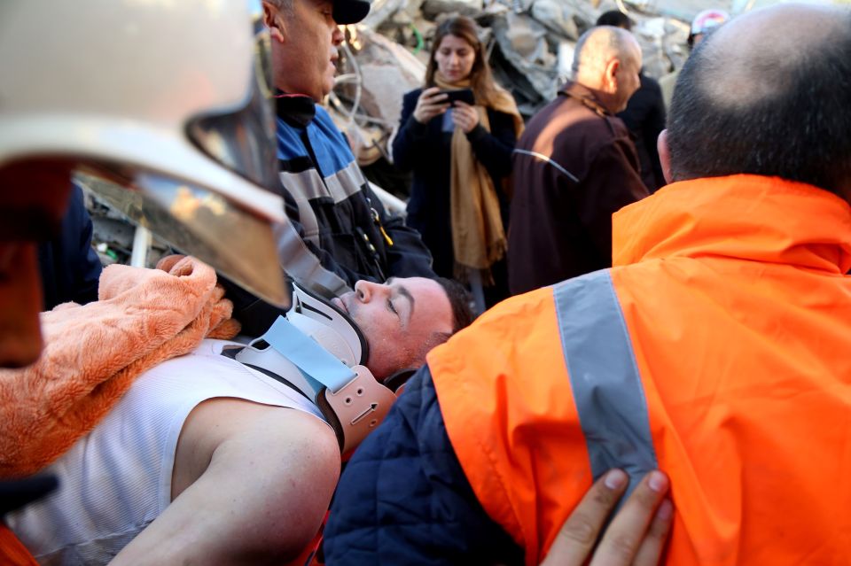  Soldiers and rescue workers carry an injured man found in debris of a collapsed building in Thumane