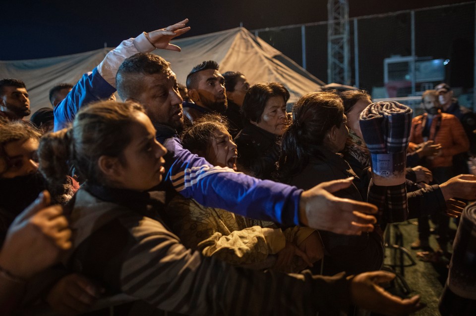  People try to receive blankets provided by volunteers at a makeshift camp in a soccer field, following a deadly earthquake in Durres, Albania