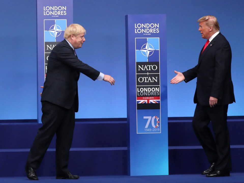  Mr Johnson and Donald Trump reach out to shake hands at the Nato summit in Watford