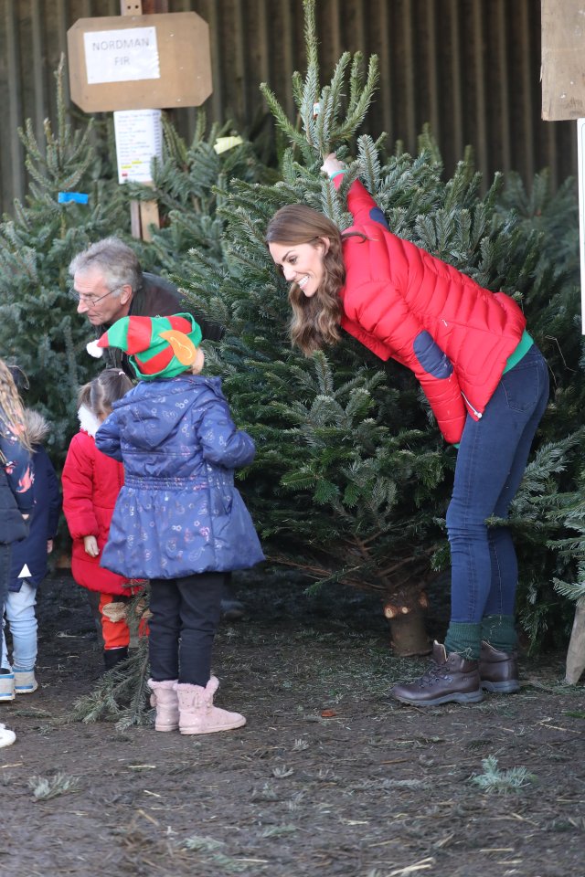 The duchess bends down to chat to one of the young children at the farm