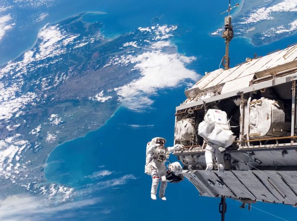  Astronauts work outside the International Space Station with New Zealand and the Cook Strait in the Pacific Ocean in the background