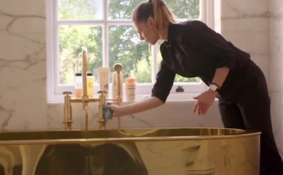  A golden bath tub sits in front of a huge window