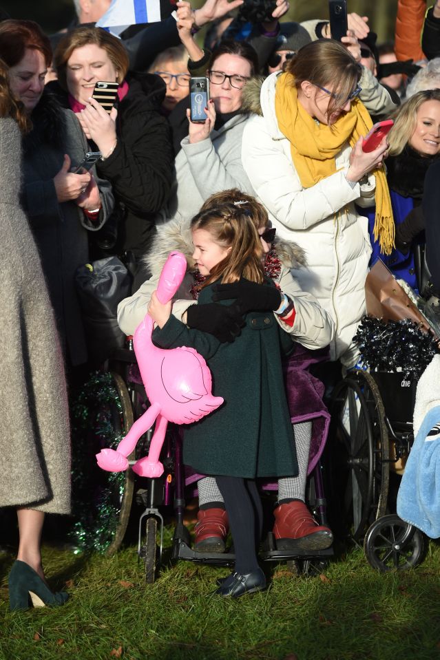  Charlotte, clutching a pink flamingo, hugs a well wisher