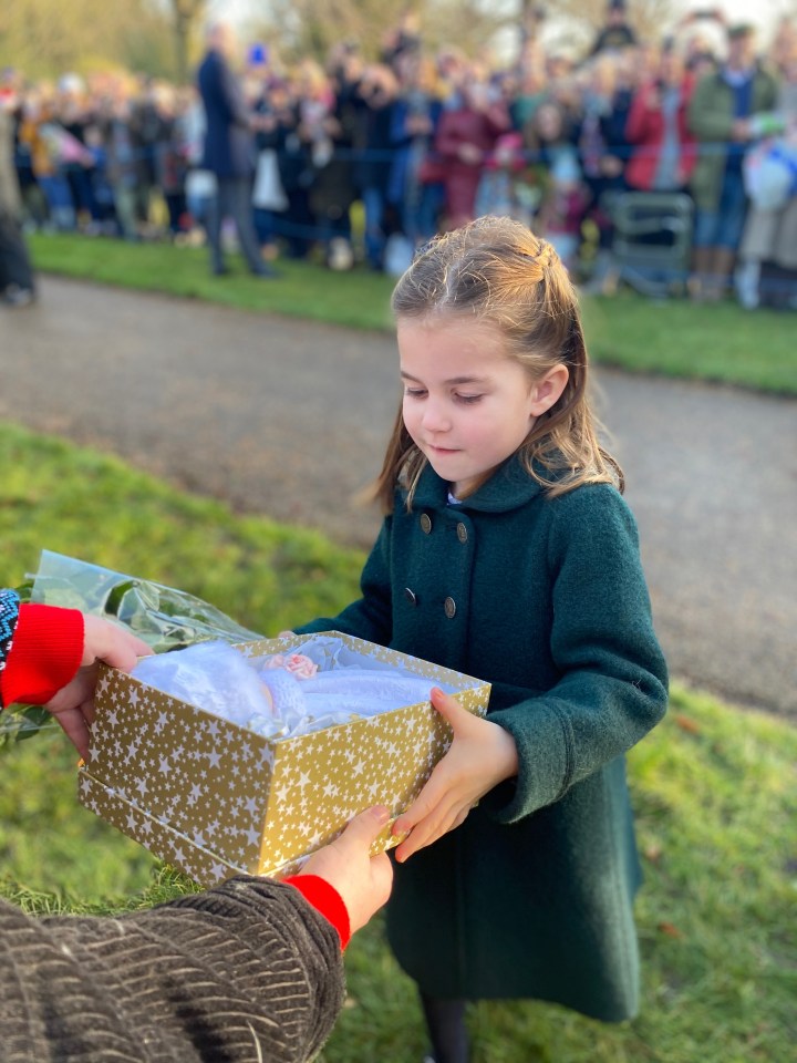  Princess Charlotte is handed a Christmas gift from a well-wisher