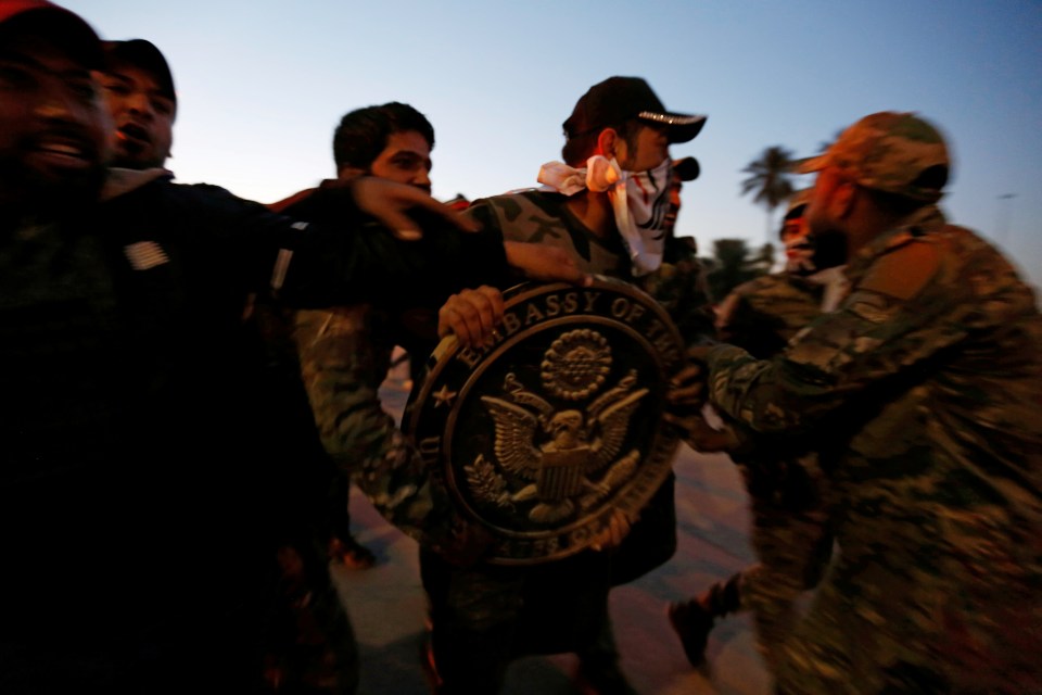  A Shia thug brandishes a US diplomatic crest looted from the embassy in Baghdad today