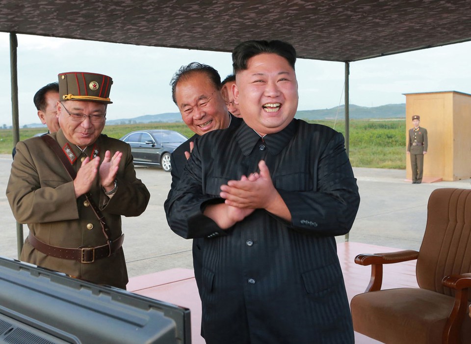  North Korean leader Kim Jong-un, right, celebrates the test launch of an intermediate range Hwasong-12 missile at an undisclosed location