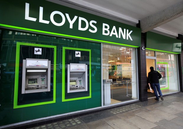 a lloyds bank with a man walking in front of it