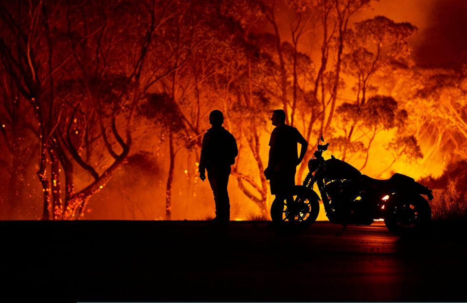  Residents look on as flames burn through bush in Lake Tabourie