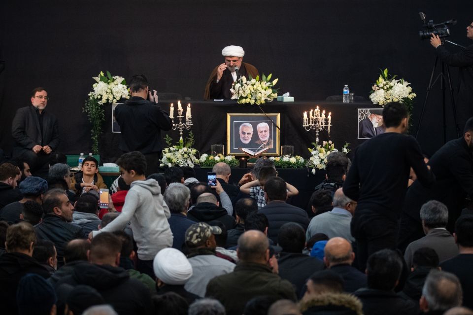  Mourners sit beneath a picture of Soleimani and Abu Mahdi al-Muhandis at the Islamic Centre of England