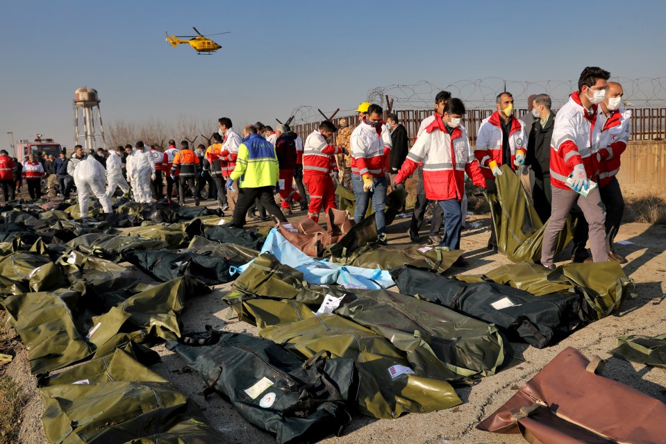  Rescue workers walk past rows of body bags at the scene of the plane tragedy