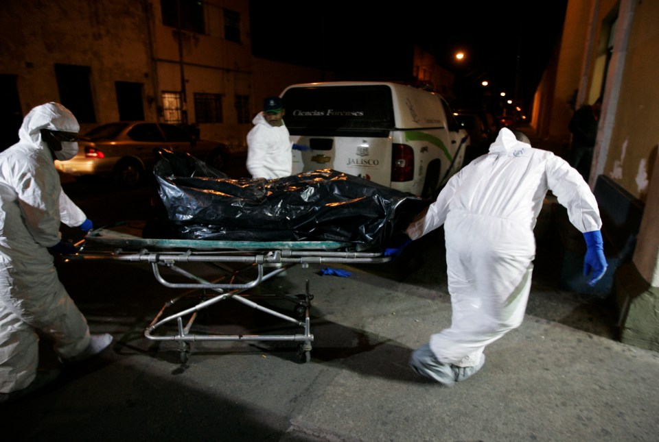 Forensic officers wheeling a body unearthed from a CJNG mass grave into the morgue in Guadalajara in 2013