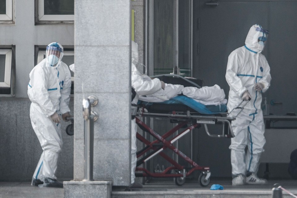 Medics in protective suits carry a patient into Jinyintan hospital in Wuhan