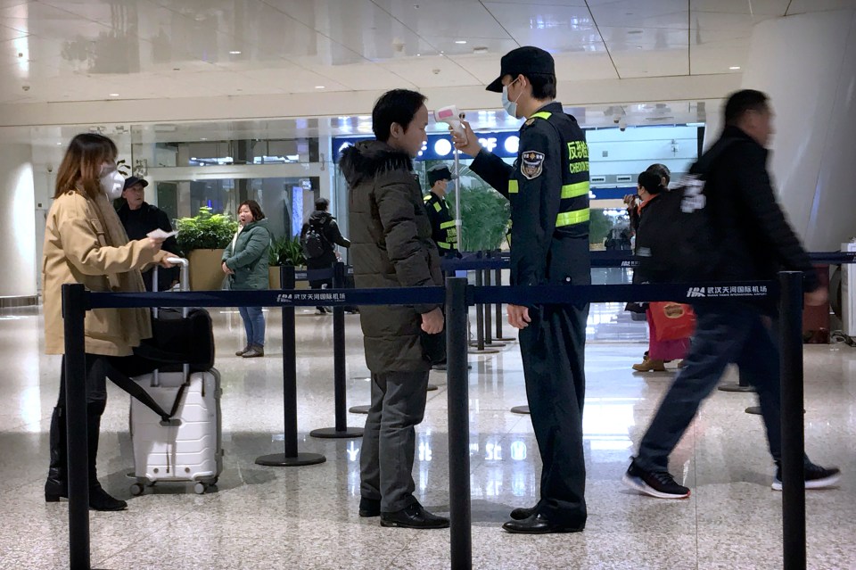  An official uses an infrared thermometer on a traveller at an airport in hard-hit Wuhan