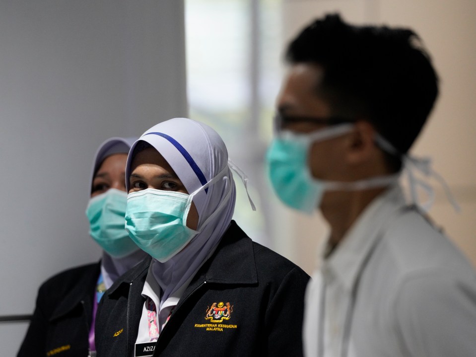 Airline staff in Kuala Lumpur war masks while members of the public are tested