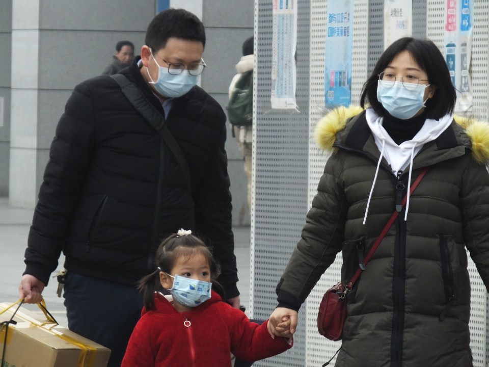  Travellers wearing protective masks walk outside a railway station in Yichang in central China's Hubei province