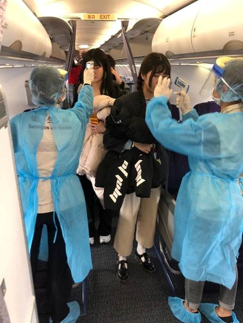  Officials measure temperatures of passengers on board on an Air China flight from Wuhan to Macau