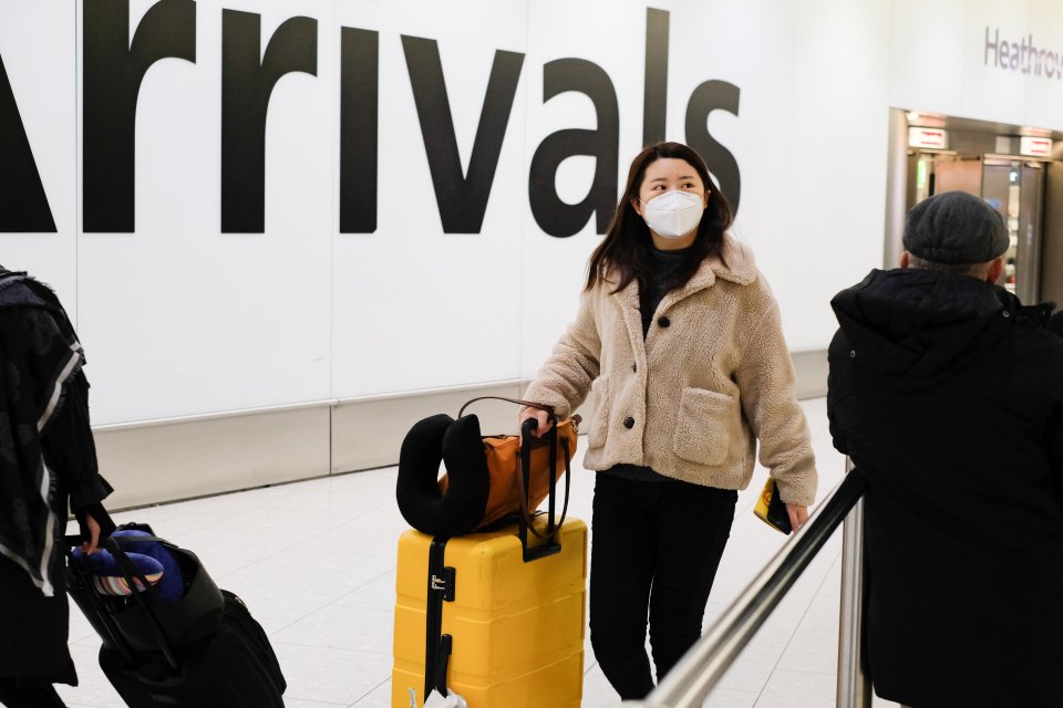  A woman arrives at London Heathrow from China on Thursday wearing a face mask