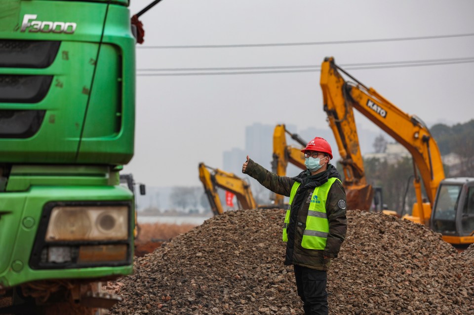  A worker gestures to a truck driver at a construction site for a makeshift hospital in Wuhan