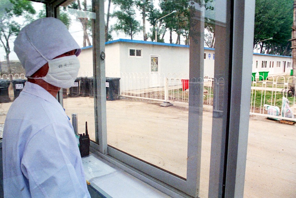  A health worker wearing a surgical mask watches looks out the window to the restricted section of the makeshift hospital built in 2003 for the SARS outbreak