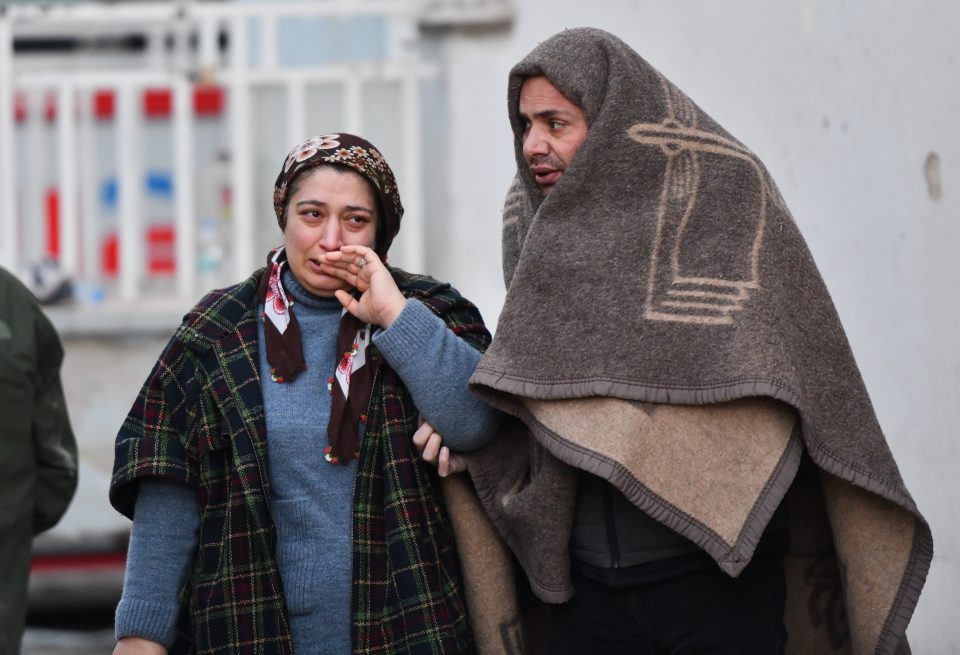  Residents wait as rescuers search the rubble for survivors