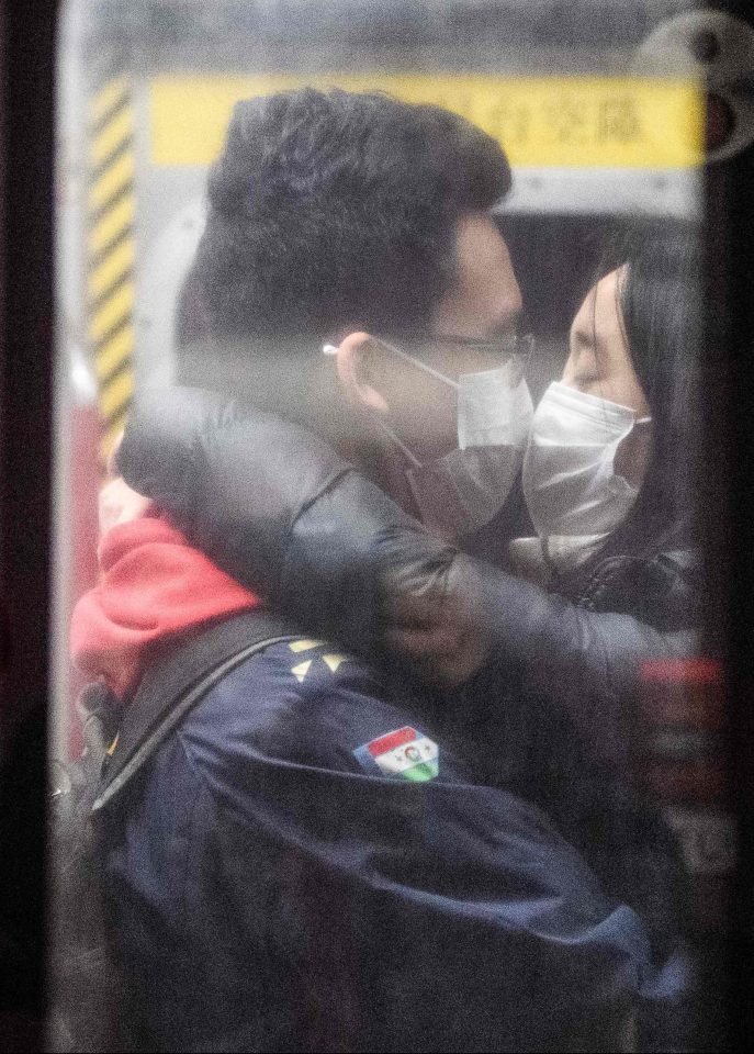  In Hong Kong, a masked couple kiss on a train