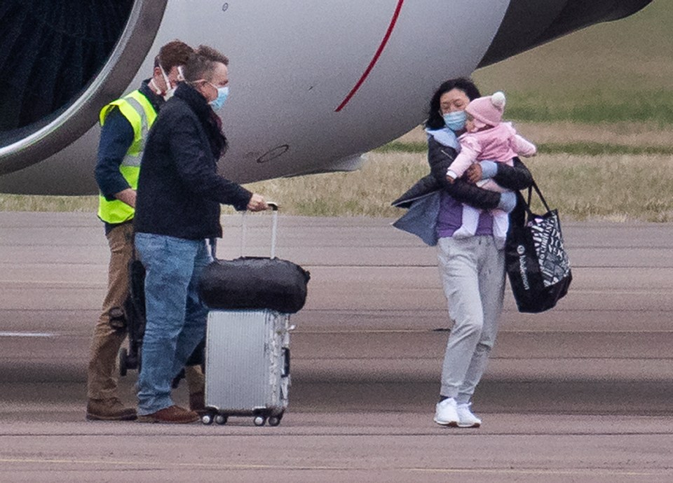  A mum carried a young girl after the Brits touched down in Oxfordshire today