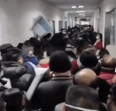 A sea of people crowd a hospital corridor as they wait to get medical treatment