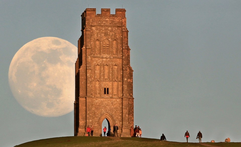 a castle tower with a full moon in the background