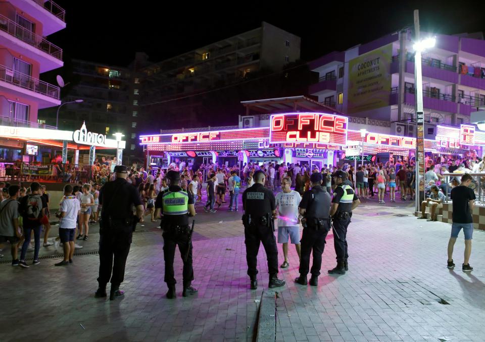  Police officers watch young British tourists enjoying at Punta Ballena, in Magaluf