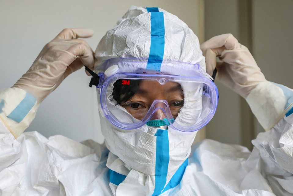 A doctor puts on a pair of protective glasses on an isolation ward in Wuhan