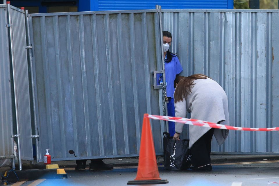  A member of staff wearing a mask comes to the entrance of the block