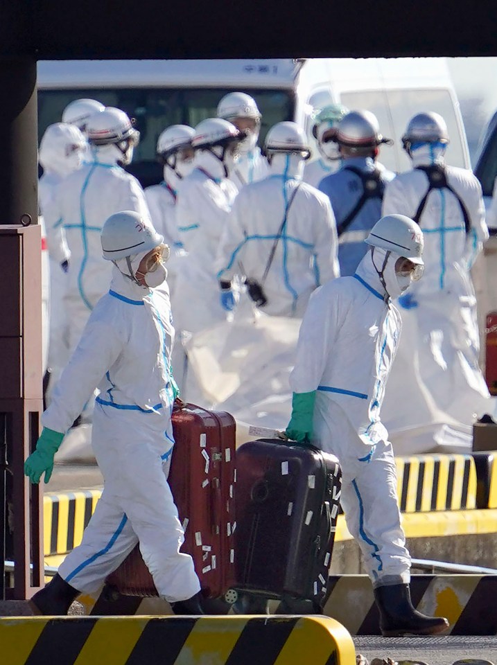 Medical workers in protective suits carry belongings of passengers of the cruise ship at Yokohama Port