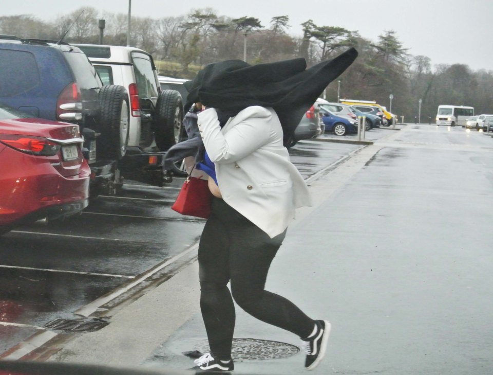  A lady caught in heavy rain and driving wind in Westport as Storm Ciara approaches the UK