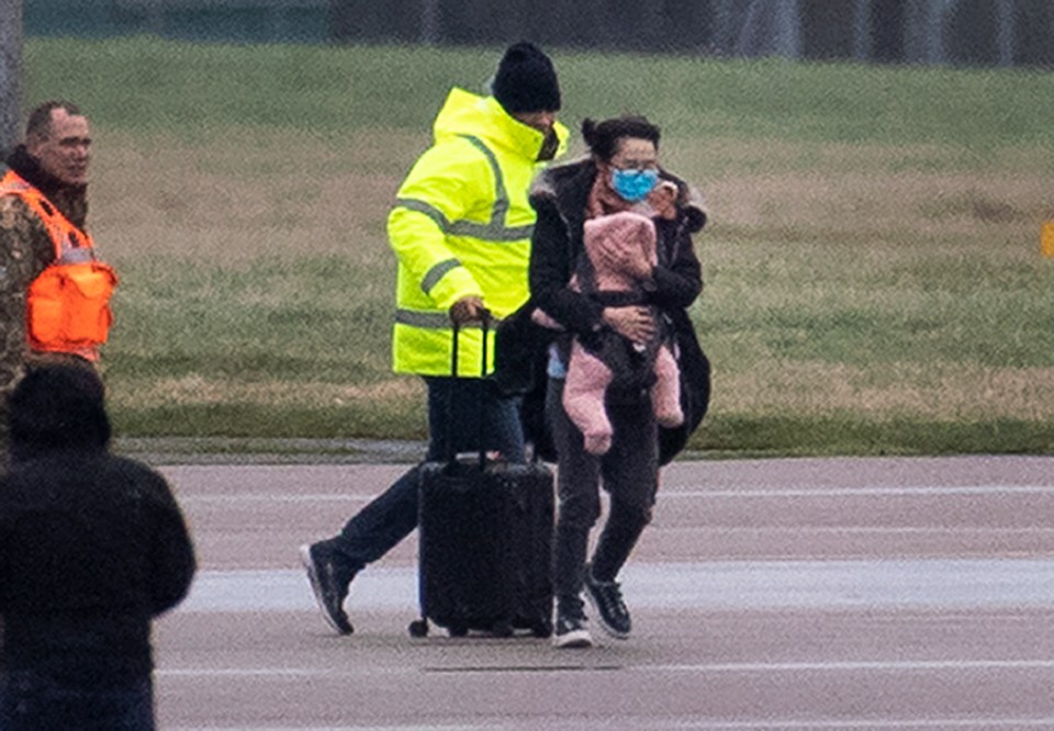 A woman carrying a baby gets off the Wuhan rescue flight