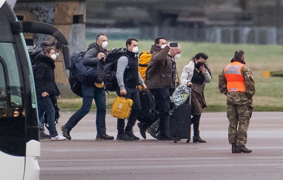 A group of evacuees walk along the tarmac