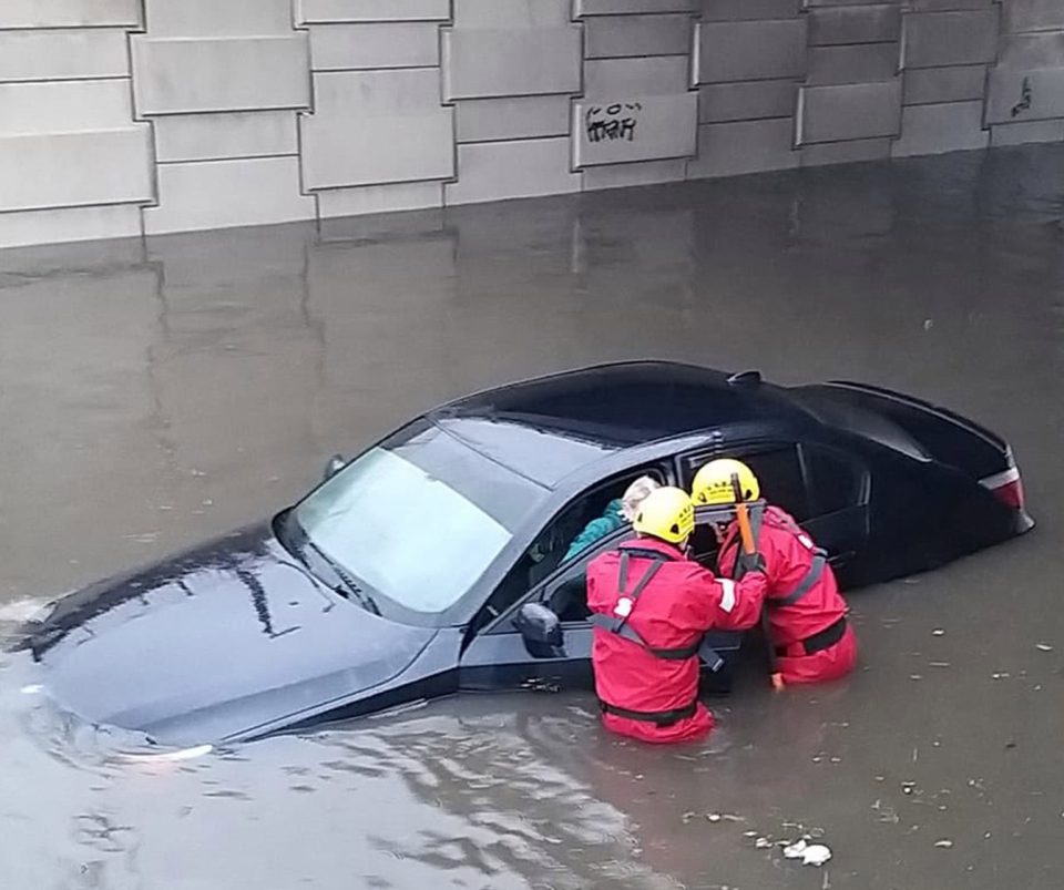  Firefighters rescuing a person from a car in a flooded street in Blackpool