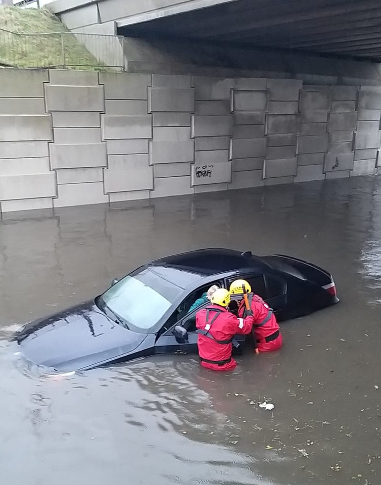 Firefighters rescuing a person from a car in a flooded street in Blackpool