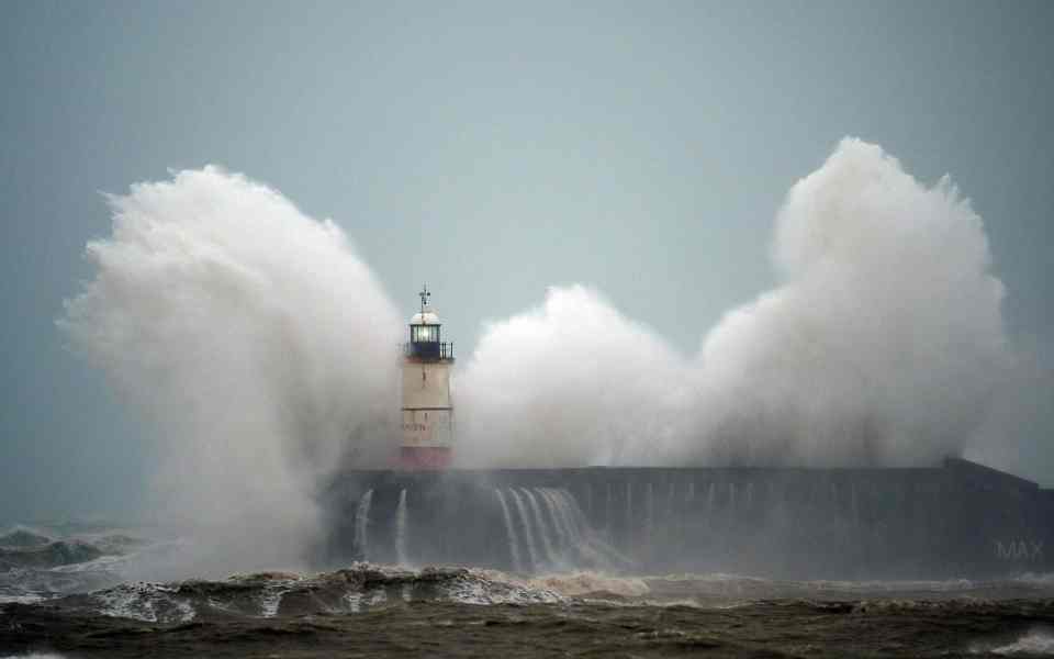  Waves crash over a lighthouse in Newhaven