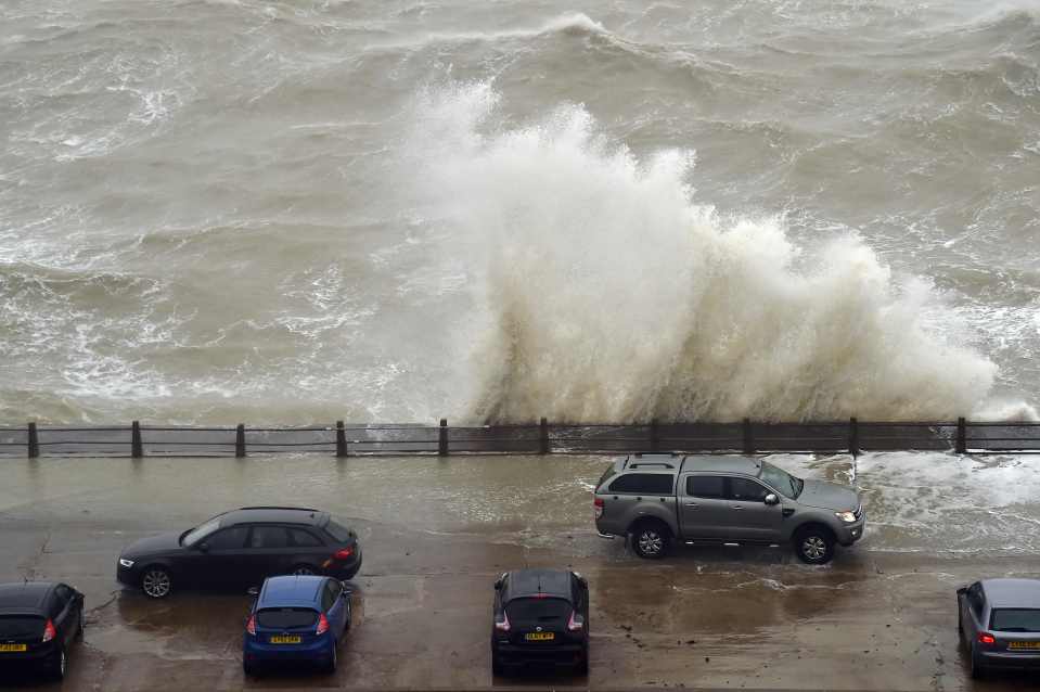  People sit in their cars to watch as they waves crash over the wall at Newhaven Harbour