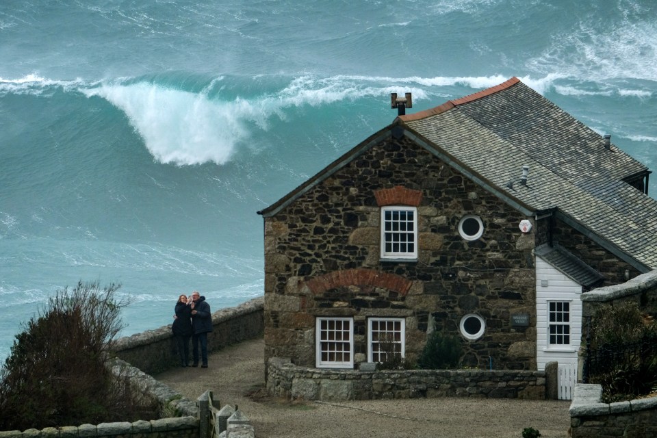  A couple take a picture of themselves in front of a massive wave in Cornwall