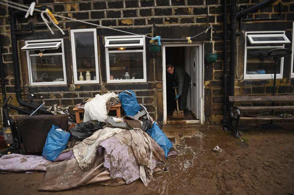  A man sweeps water from a home in Mytholmroyd, northern England