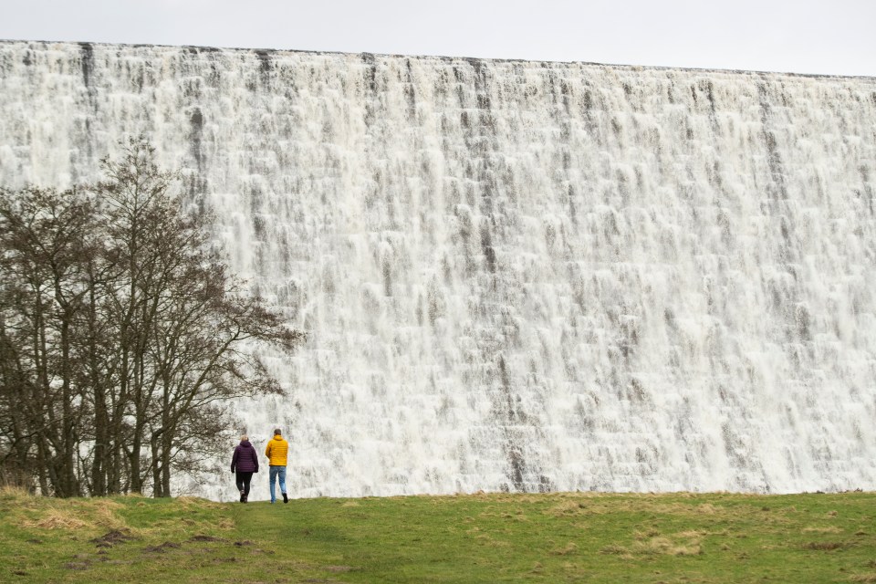  Walkers watch in awe as cascading water thunders over Derwent Reservoir Dam