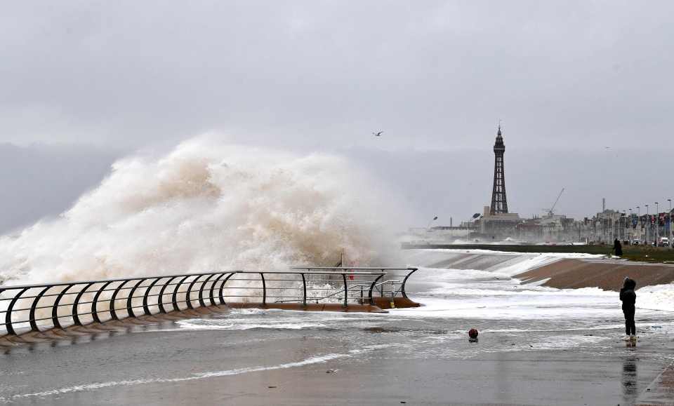  A boy stands on the promenade as waves crash over the barriers in Blackpool